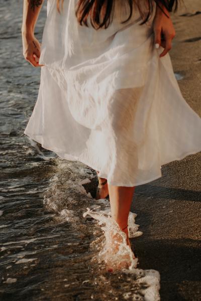女孩赤腳踏在水中的沙灘上高清圖片