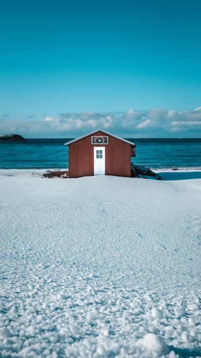 海边雪地上孤独的棕色小木屋