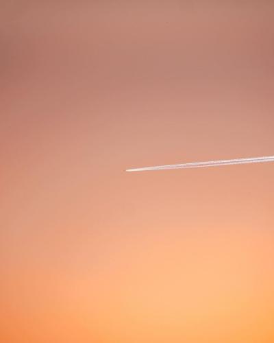 飞机穿过橙色天空留下一丝白线