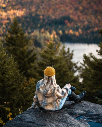 坐在巨石上看森林景色的美女