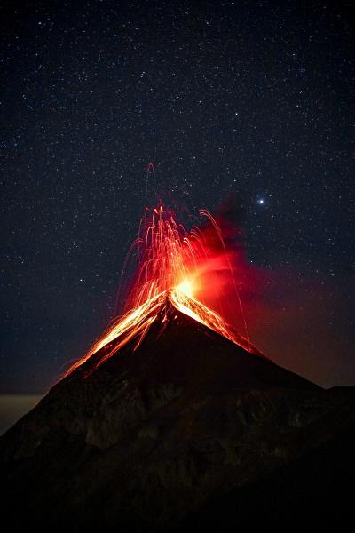 火山在夜晚满天繁星下爆发喷射