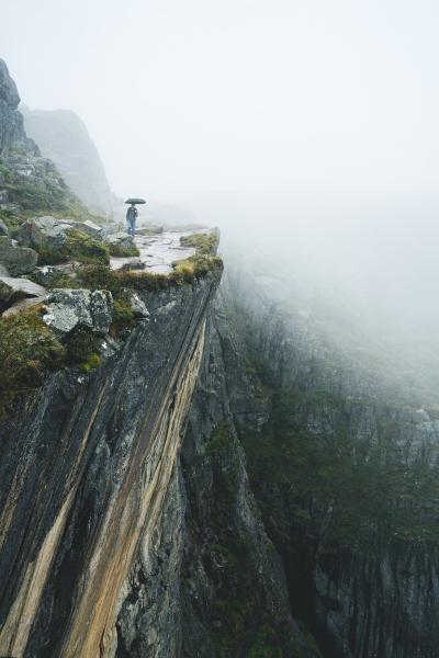 撑伞在悬崖峭壁上的男人