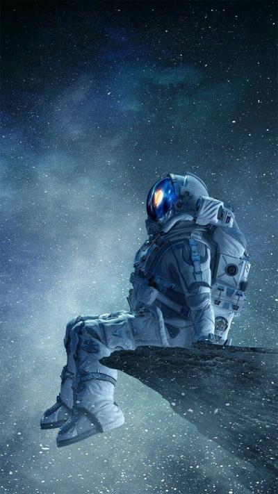 宇航员穿太空服坐在星辰里的创意图片