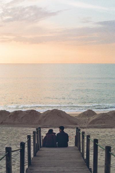 情侣坐在海边桥上看日出